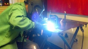 Kamal welds some bike-frame-sized scraps of pipe together.